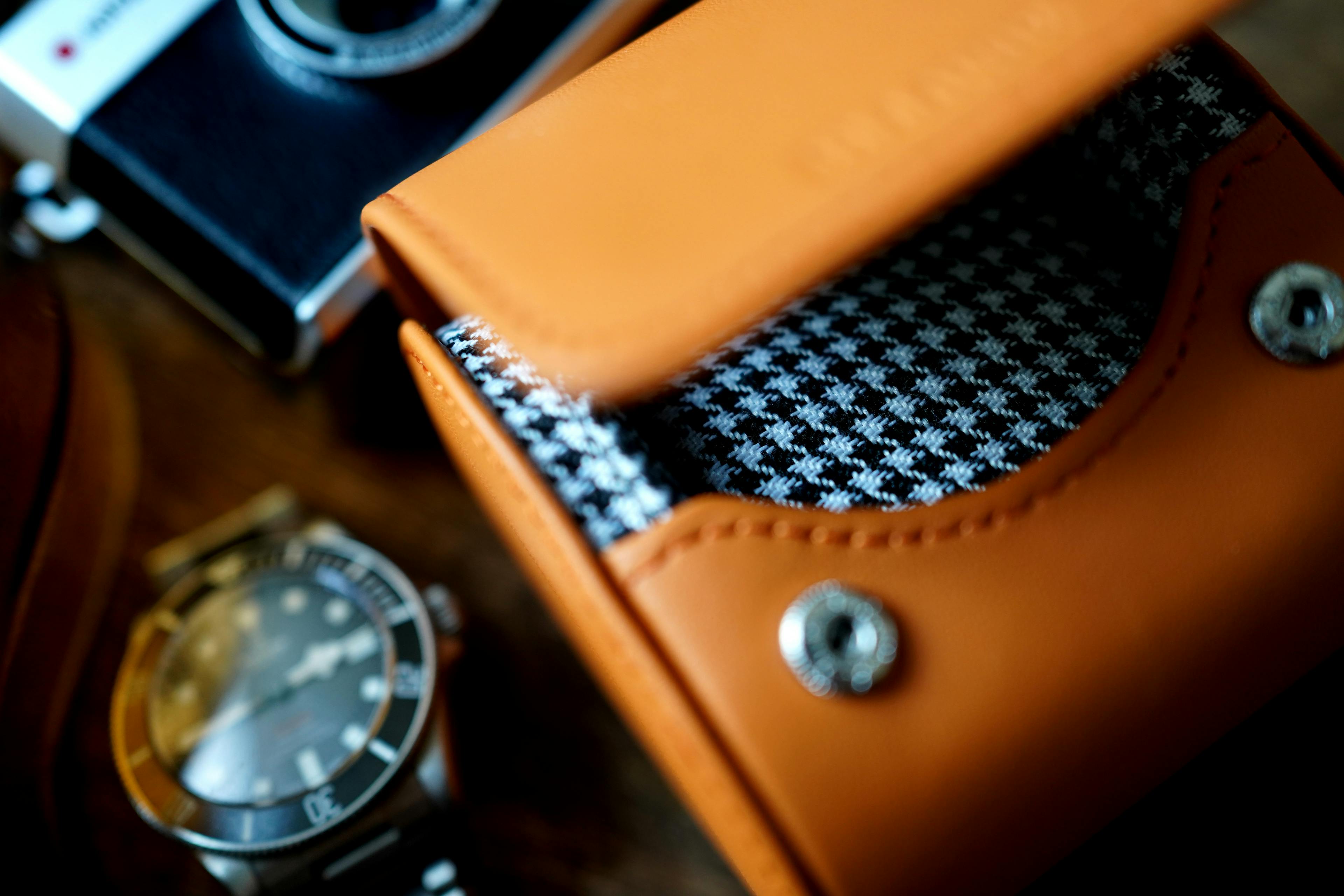 Unveil timeless elegance with our Icon Watch Case, a harmonious blend of style and protection. Crafted with an alluring Orange Leather exterior and a refined Houndstooth Cotton interior, this case redefines luxury. In this striking image, our Icon case takes center stage against a textured beige rock wall. The contrast of the case's sophistication and the rugged backdrop creates a captivating visual narrative. As you consider this masterpiece, imagine the perfect sanctuary it provides for your cherished watches, seamlessly combining fashion and functionality. Experience the iconic essence of watch storage like never before.