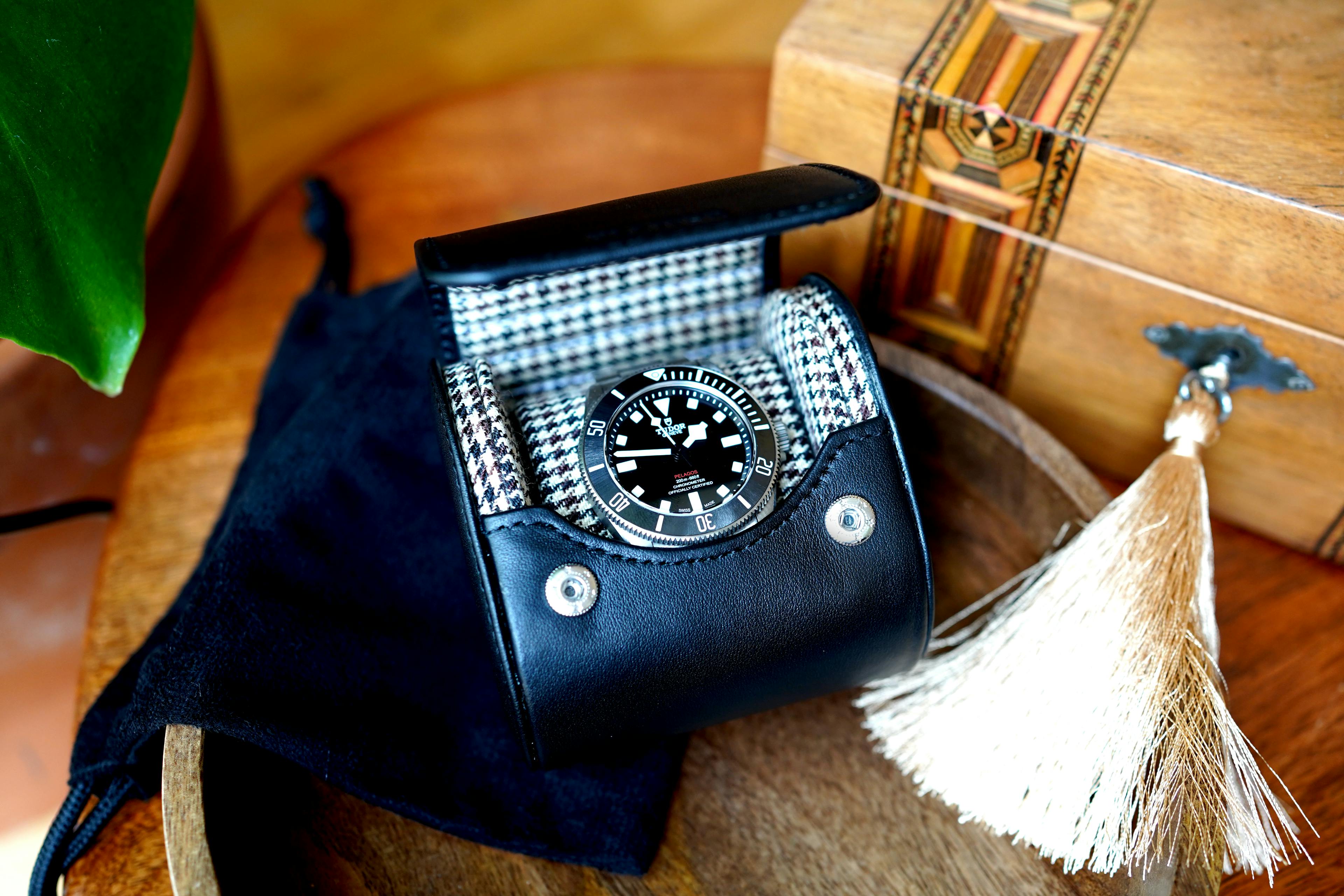 Experience the epitome of luxury and style with our Noir Luxury Watch Case. This exceptional case features a timeless Black Leather exterior and a distinguished Black and Brown Tartan Interior, blending sophistication with functionality effortlessly. Crafted with meticulous attention to detail, it stands as the ultimate protector of your treasured timepieces.

In this captivating scene, our Noir case takes center stage on an outdoor table, framed by the warm glow of a crackling fire and leaning gracefully against a stainless steel wine chiller. The juxtaposition of rugged outdoor elements and refined craftsmanship creates a striking visual narrative. Imagine your watches resting inside, cradled by the sumptuous tartan lining, as you savor the moment by the fireside.

Indulge in the world of luxury watch storage, where every aspect is carefully designed to ensure your watches are not only secure but also beautifully displayed. Whether it's a personal indulgence or a thoughtful gift, our Noir case encapsulates the essence of sophistication and safeguarding. Discover the perfect companion for your watches, where elegance meets the great outdoors.