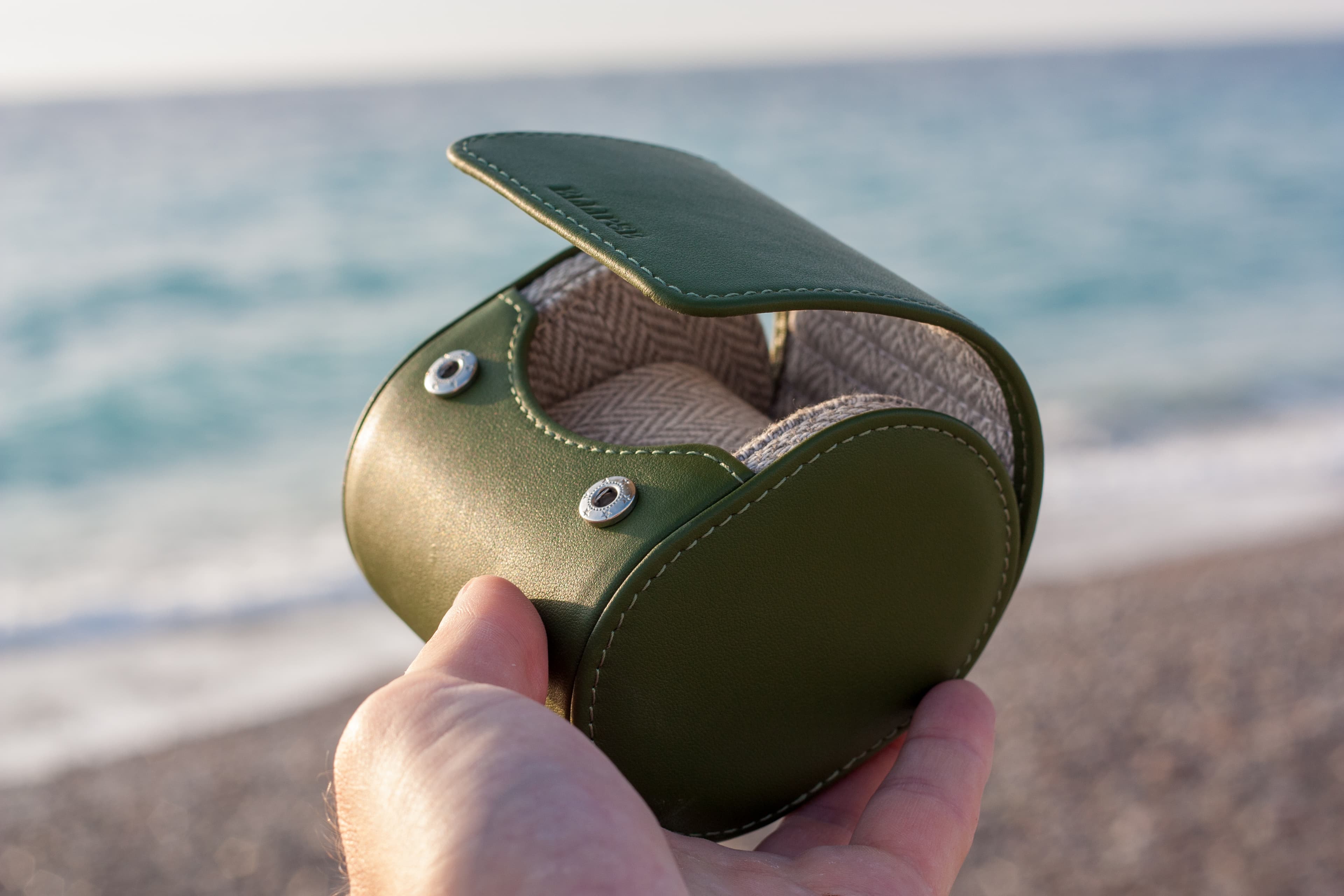 Introducing the Evergreen Luxury Watch Travel Roll – where timeless elegance meets impeccable craftsmanship. This exceptional case showcases a striking Green Leather exterior paired with a sophisticated Grey and White Chevron Patterned Interior, perfectly blending style and security for your cherished timepieces.
In this impeccable creation, the beauty of the outdoors harmonizes with the precision of watch storage. Picture the Evergreen case being held up in front of the serene sea, while the sun sets in a breathtaking display of colors. This moment captures the essence of our Evergreen case, ensuring your watches are both safeguarded and beautifully displayed no matter where your travels take you. The lush green leather exterior embodies luxury, while the chevron patterned interior adds a touch of modern sophistication.
Whether you're a jet-setting globetrotter or simply want to protect your watches with the utmost care, the Evergreen Luxury Watch Travel Roll is your ideal companion. Explore a world where your watches travel in impeccable style, safe in the knowledge that every detail has been considered. Discover the essence of luxury and protection with our Evergreen case.